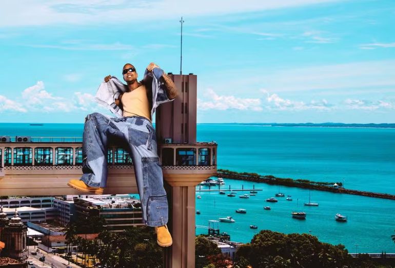 O cantor Léo Santana em um palco, com pose de "GG", anunciando um show de celebração de 20 anos de carreira.