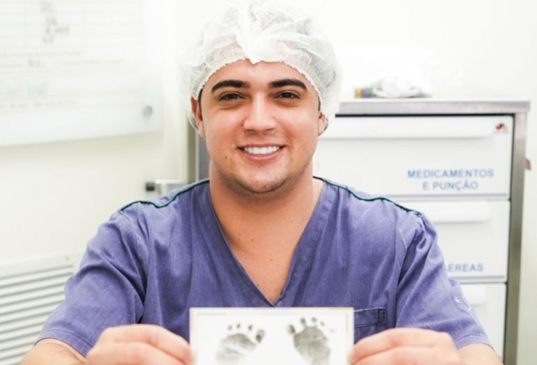 O cantor Natanzinho Lima segurando o teste do pezinho do seu filho recém-nascido, Ravi, no hospital.